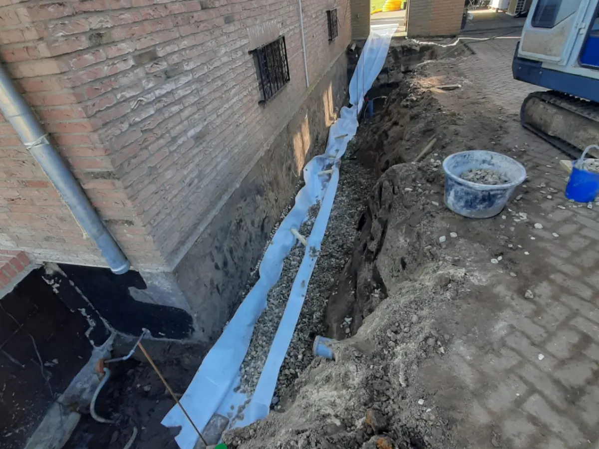 Drainageaufbau mit Filtervlies und Kiesbett entlang einer abgedichteten Hauswand