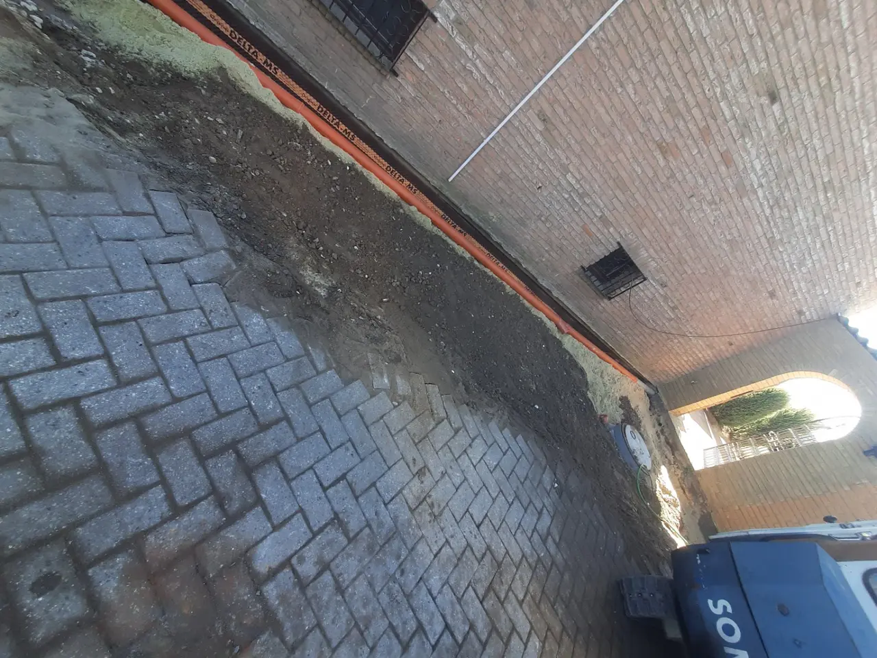 Rohrleitung und Schutzschicht entlang einer Hauswand mit vorbereitetem Schachtanschluss