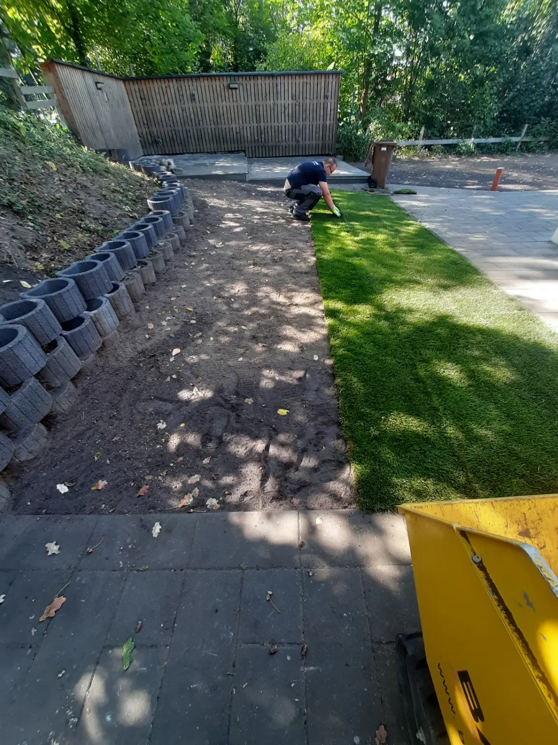 Mitarbeiter beim Verlegen von Rollrasen auf einer vorbereiteten Gartenfläche