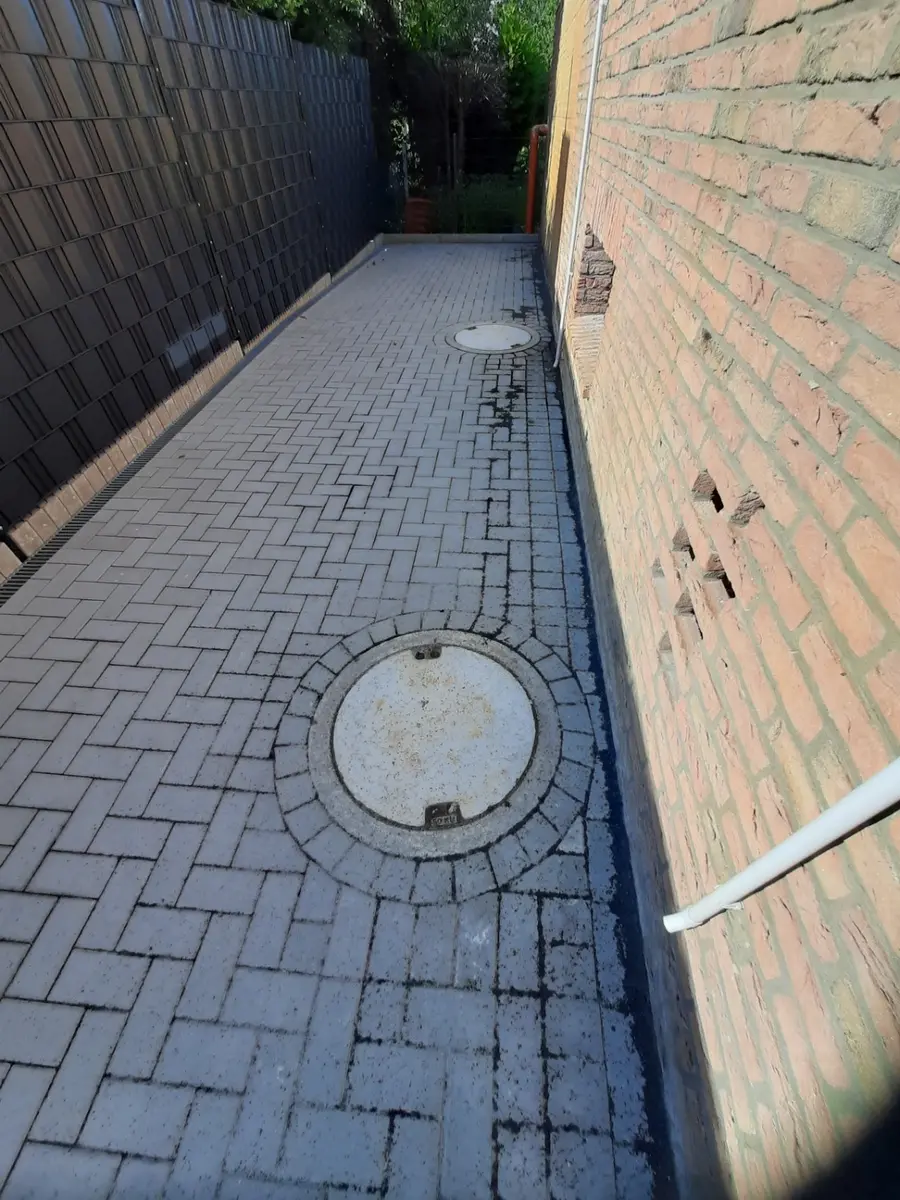 Zwei runde Schachtdeckel sauber in eine graue Pflasterfläche eingebunden