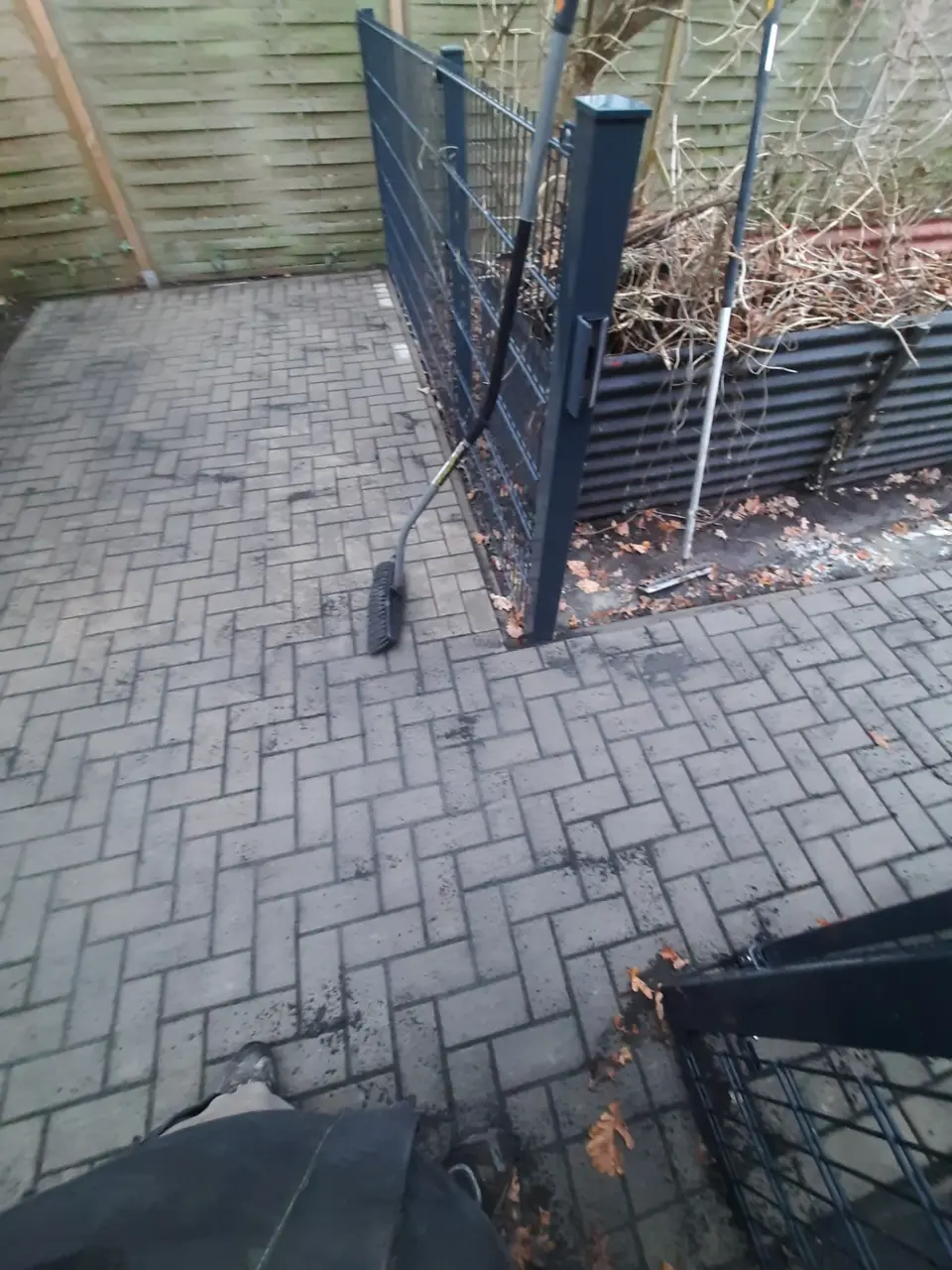 Detailansicht einer Pflasterfläche mit sauberem Anschluss an Zaunpfosten und Einfassung